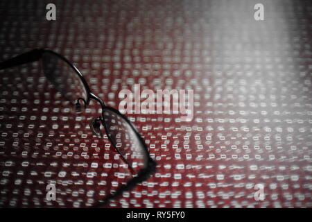computer hacker. red dangerous code breach into red binary code with glasses place over led panel. virus, cyber threat and computer internet system fa Stock Photo