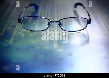 big data analysis. glasses placed on a LED digital panel display white light one and zero binary text number in moving motion pattern. modern technolo Stock Photo