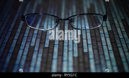 big data analysis. glasses placed on a LED digital panel display white light one and zero binary text number in moving motion pattern. modern technolo Stock Photo