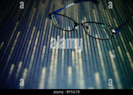 big data analysis. glasses placed on a LED digital panel display white light one and zero binary text number in moving motion pattern. modern technolo Stock Photo