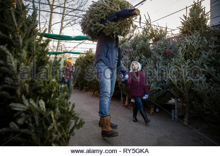 Father and daughter carrying christmas tree at christmas market