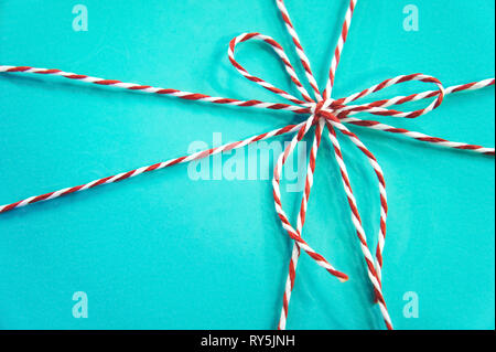 Turquoise gift box background. red and white rope bow on a blue background. Stock Photo