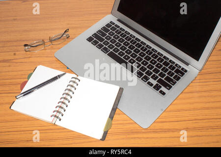 Desk with open notepad, pen, eye glasses, nicely placed on office table. Top view with copy space. Business still life concept with office stuff on ta Stock Photo