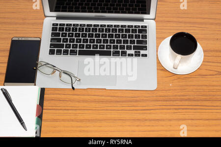 Desk with open notebook, mobile phone, eye glasses, and morning cup of coffee. Top view with copy space. Business still life concept with office stuff Stock Photo