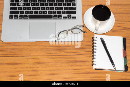 Desk with open notebook with blank pages, eye glasses, pen and a cup of coffee. Top view with copy space. Business still life concept with office stuf Stock Photo