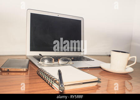 Desk with open notebook, mobile phone, eye glasses, pen and a cup of coffee. Top view with copy space. Business still life concept with office stuff o Stock Photo