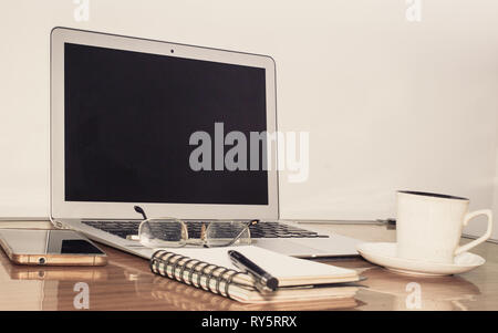 Desk with open notebook, mobile phone, eye glasses, pen and a cup of coffee. Top view with copy space. Business still life concept with office stuff o Stock Photo