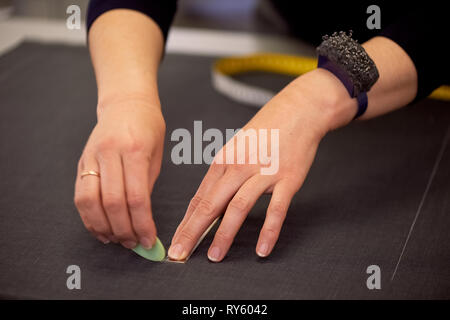 The seamstress lays out the fine scheme for cutting fabric.Tailoring in the Studio Stock Photo