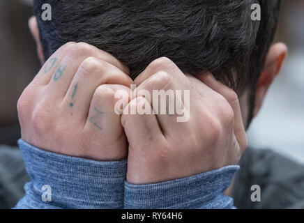 Wiesbaden, Germany. 12th Mar, 2019. 21-year-old Ali B. covers his face at the start of the trial. The criminal court accuses the refugee from Iraq of having raped and murdered 14-year-old Susanna from Mainz last May. After his escape to Iraq, the alleged perpetrator was brought back to Germany a few days later. Credit: Boris Roessler/dpa/Alamy Live News Stock Photo