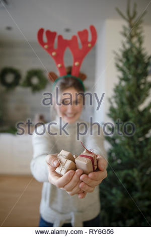 Portrait teenage girl in reindeer antlers holding small christmas gifts Portrait teenage girl in reindeer antlers holding small christmas gifts