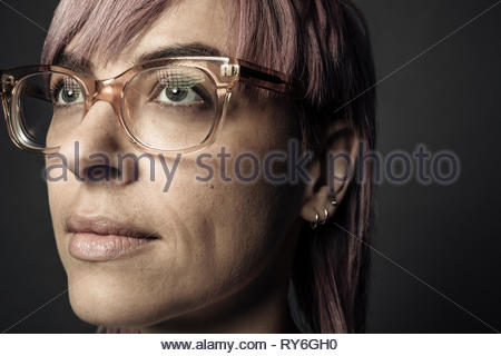 Close up portrait confident beautiful non-binary gender person with pink hair and eyeglasses