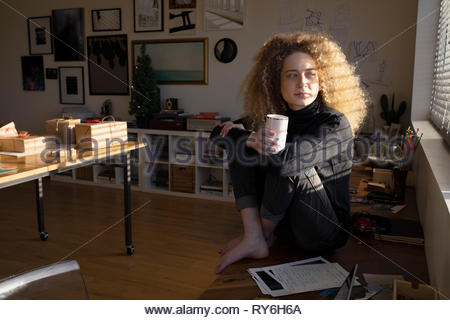 Thoughtful young woman drinking coffee in studio