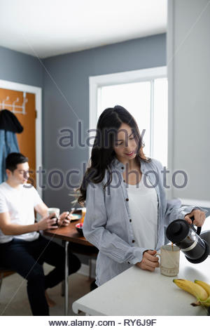 Young Latinx woman pouring coffee in morning kitchen