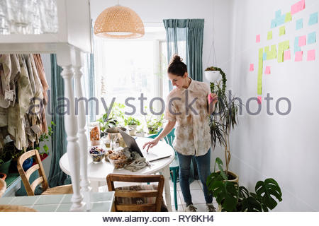 Female artist with laptop planning with adhesive notes