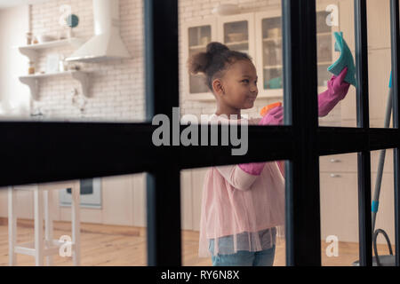 Beautiful stylish girl wearing pink blouse cleaning the glass door Stock Photo
