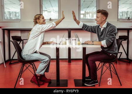 Smiling positive co-workers giving each other high five Stock Photo