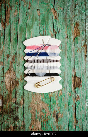 Overhead view of colorful threads with buttons and needle on wooden table Stock Photo