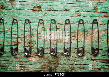 Overhead view of safety pins arranged on old wooden table Stock Photo