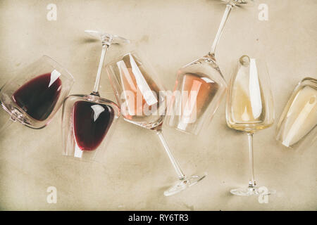 Red, rose and white wine in glasses over grey background Stock Photo