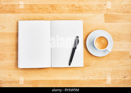 Blank notebook, pen and cup of coffee or espresso on yellow wooden table. Office concept. Top view. Copy space for text. Flat lay. Stock Photo