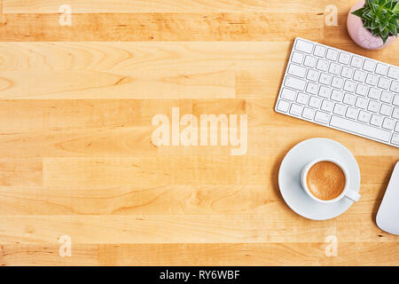 Cup of coffee or espresso with keyboard, mouse and plant on yellow wooden table. Office desktop concept. Top view. Copy space for text. Flat lay. Stock Photo