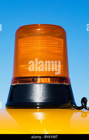 Magnetic Flashing occluding orange beacon on a bright yellow vehicle roof. Stock Photo