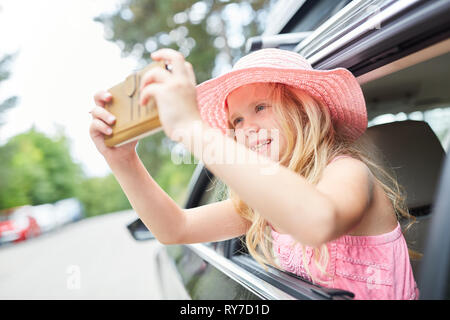 Girl in the car takes a selfie photo out the side window while driving Stock Photo