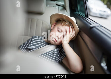 Boy with hat is sleeping on the back seat in the car on the road trip on vacation Stock Photo