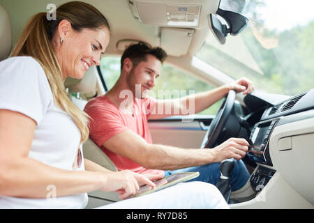 Happy couple driving in car using tablet computer as navigation system Stock Photo
