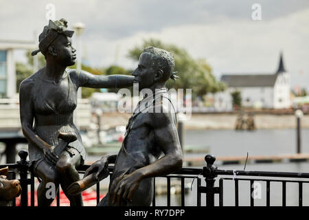 John Clinch's sculpture 'People Like Us' in Mermaid Quay with the Norwegian Church in the background, Cardiff Bay, Wales. Stock Photo