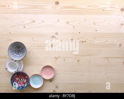 different kinds of modern colourful crockery on light wood background Stock Photo