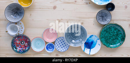 different kinds of modern colourful crockery on light wood background Stock Photo