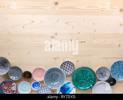 different kinds of modern colourful crockery on light wood background Stock Photo