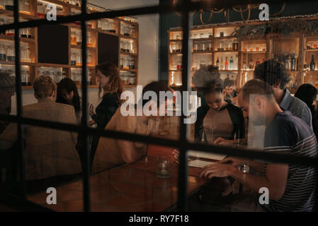 Diverse young friends ordering drinks in a bar at night Stock Photo