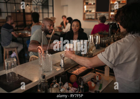 Young couple having drinks at a bar in the evening Stock Photo