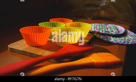 Silicone brush and cupcake liners on wooden table. Kitchen and cooking concept on wooden background Stock Photo