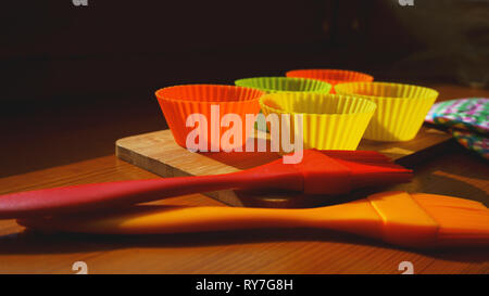 Silicone brush and cupcake liners on wooden table. Kitchen and cooking concept on wooden background Stock Photo