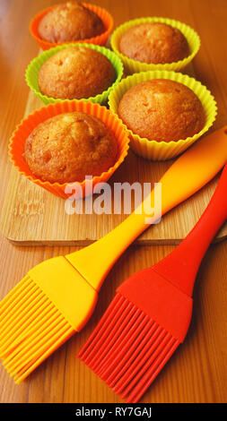 Simple mini muffins in colorful silicone bakeware. Silicone cup baking cupcakes and silicone brushes. Kitchen and cooking concept on wooden background Stock Photo