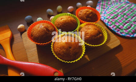 Mini Cakes Decorated with Eggs, Easter Dessert. Simple mini muffins in colorful silicone bakeware. Kitchen and cooking concept on wooden background Stock Photo