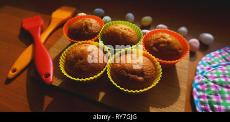 Mini Cakes Decorated with Eggs, Easter Dessert. Simple mini muffins in colorful silicone bakeware. Kitchen and cooking concept on wooden background Stock Photo