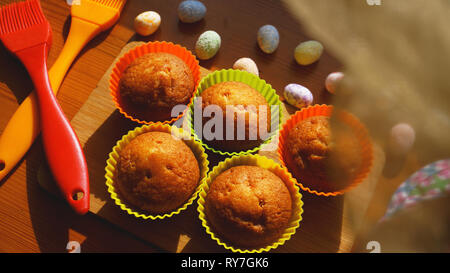 Mini Cakes Decorated with Eggs, Easter Dessert. Simple mini muffins in colorful silicone bakeware. Kitchen and cooking concept on wooden background Stock Photo