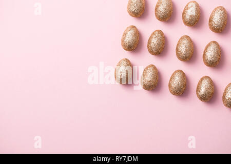 Gold glitter easter eggs on a pastel pink background. Happy Easter Stock Photo
