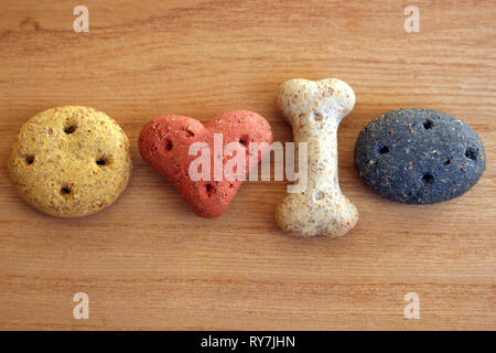 Differently shaped and coloured dog biscuits on a wooden background Stock Photo