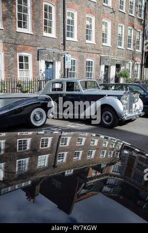 A 1964 Empress Bentley and a 1954 Rolls-Royce Silver Dawn are parked in Smith Square, a small square behind the Houses of Parliament, before collecting their VIP passengers - barristers who are being sworn in as QCs (aka Silks in legal vernacular), on 11th March 2019, in London, England. Stock Photo