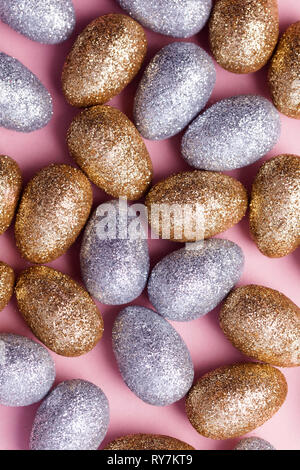 Gold and silver glitter easter eggs on a pastel pink background. Stock Photo