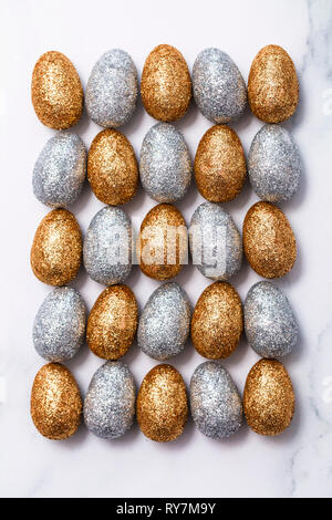 Gold and silver glitter easter eggs on a marble background