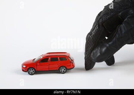 A gloved hand moves quietly toward a (miniature) car to steal it. Stock Photo