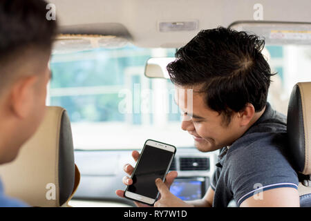 Online taxi driver  showing smartphone for paying and give direction inside car Stock Photo