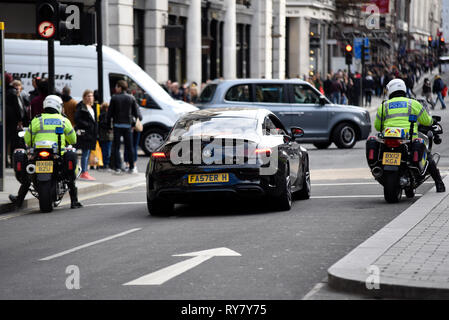 AMG Mercedes Benz C63 C Class with the number plate Faster H registration FA57ERH. Executive performance car with police motorcycle riders looking Stock Photo