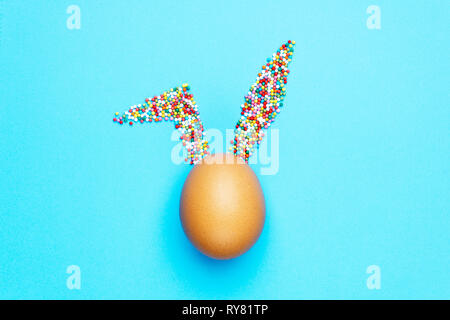 Minimal concept Easter. Egg with rabbit ears of sweets on colored background. Сreative design concept Stock Photo